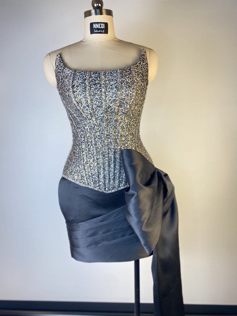 Kurzes Kleid mit silbrig glitzerndem Korsagenoberteil und grauer Taftdrapierung auf einer Schneiderpuppe