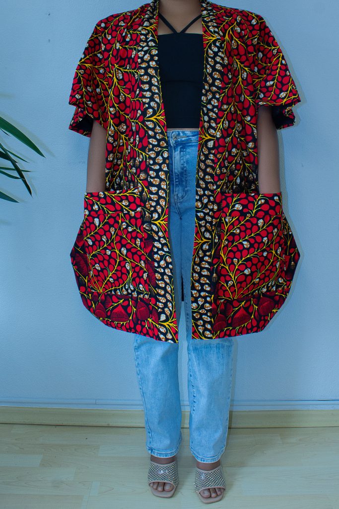 Weit geschnittene Bubu-Jacke aus rotem Wachsdruckstoff, von vorne über einer Jeans getragen